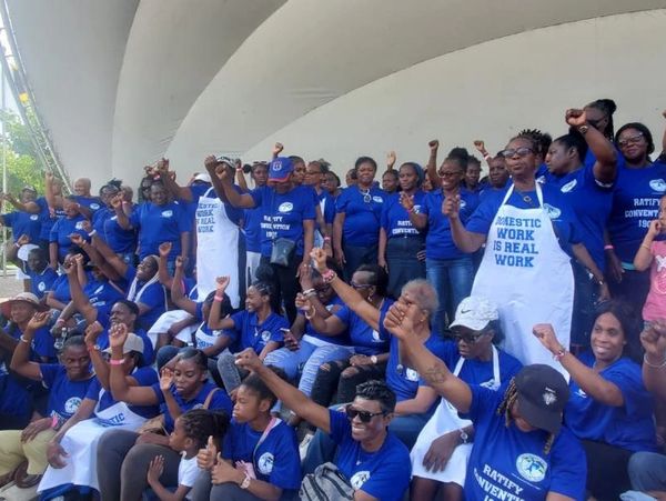 A large group in blue shirts and aprons raising fists in solidarity.