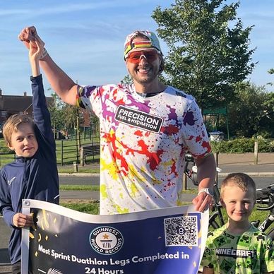 Smiling man with two kids holding a Guinness World Record banner.