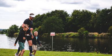 Man and two kids walking near a pond.