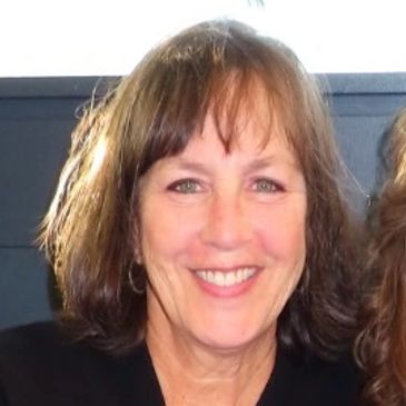 Smiling woman with glasses and wavy hair.