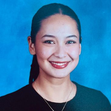 Young woman smiling against a blue background.
