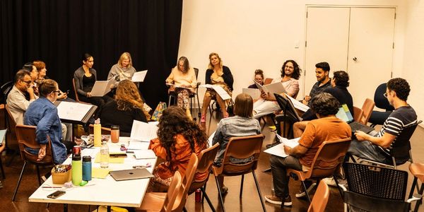 Group of people in a circle having a discussion or rehearsal.