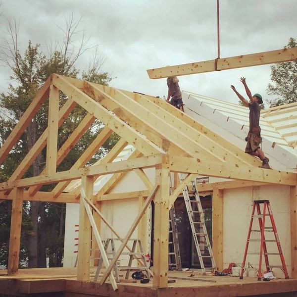 Workers constructing a wooden roof frame on a building site.