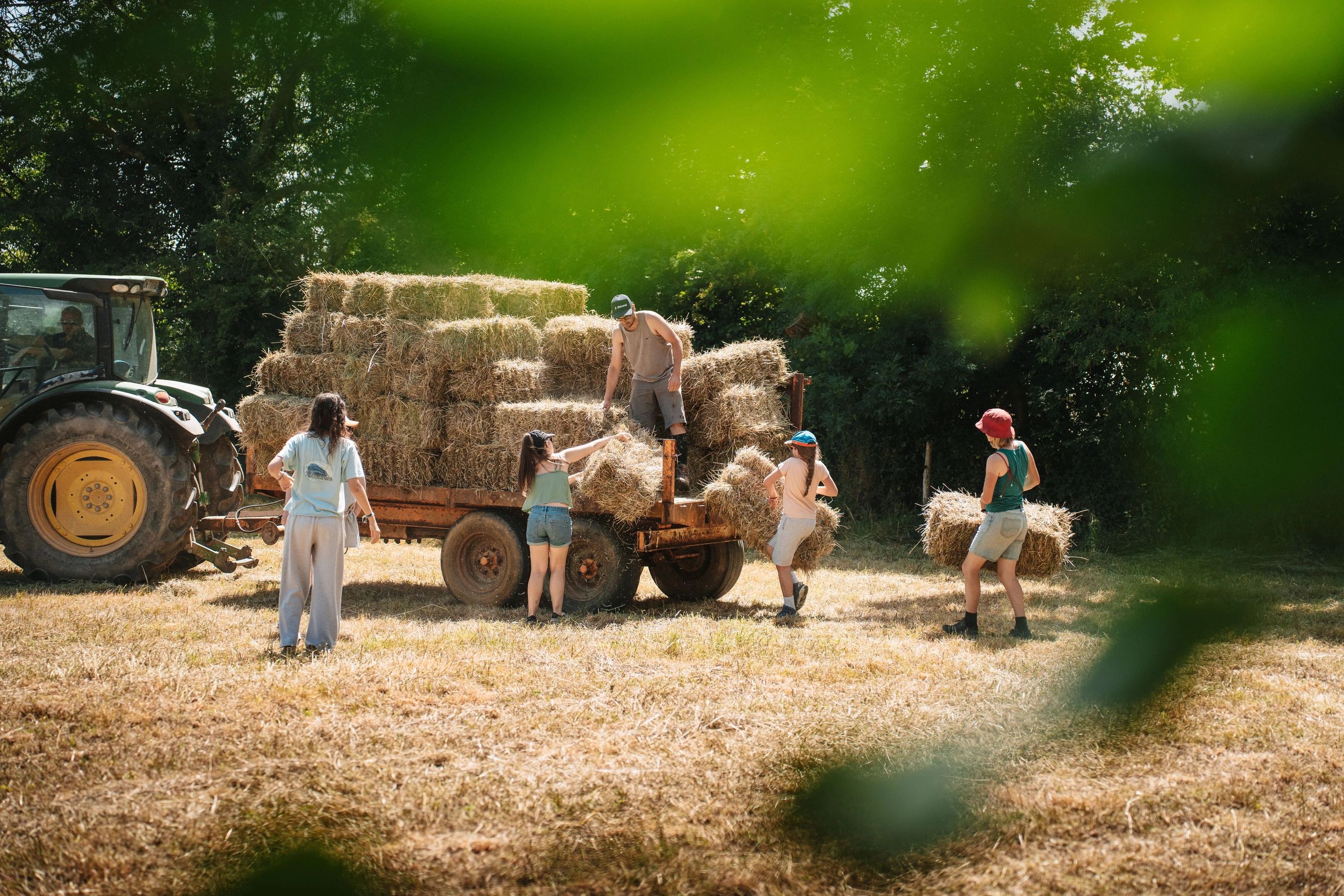 People unloading hay bales from a tractor trailer.