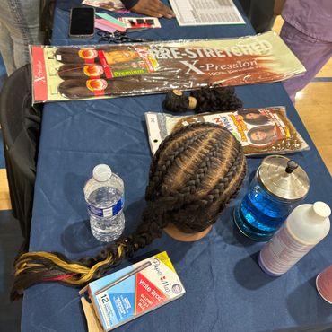 Hair braiding display on a table with products.