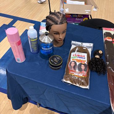 Table with hair products and a mannequin head with cornrow braids.