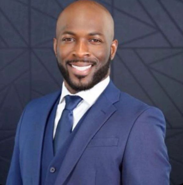 Man in a blue suit smiling confidently.