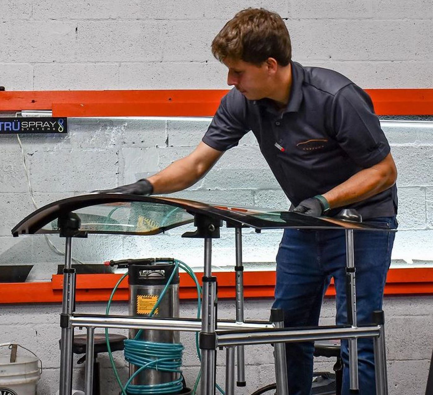 Expert window tinting instructor applying tint to a car windshield at our training facility in Davie