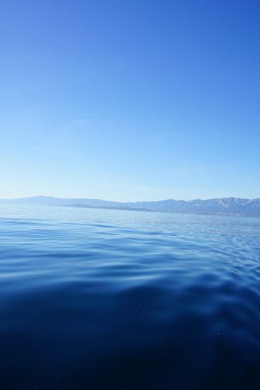 Calm blue lake with distant mountains under a clear sky.