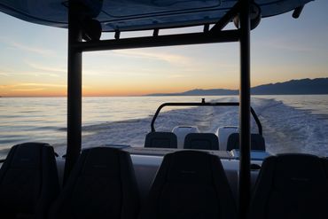 View from a boat cruising at sunset with empty seats in the foreground.