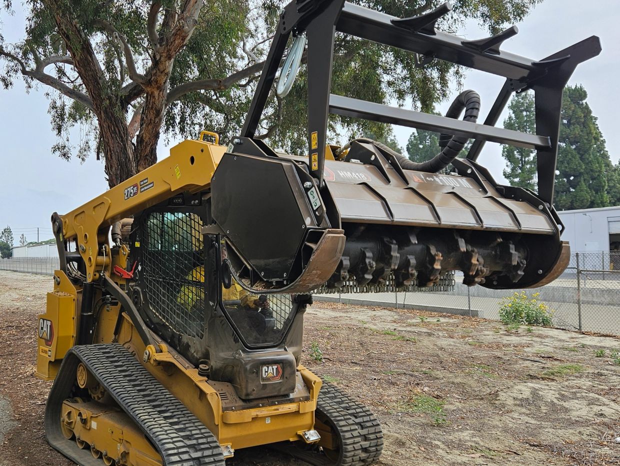 Yellow Caterpillar 275 skid steer with mulcher attachment.