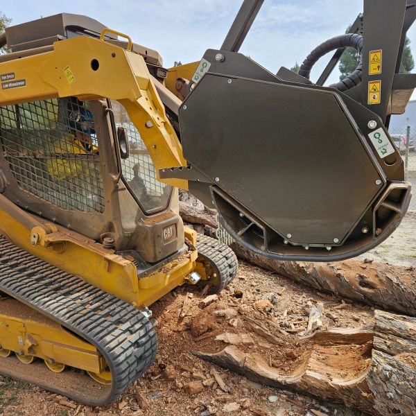 Yellow skid steer loader with wood chipping attachment