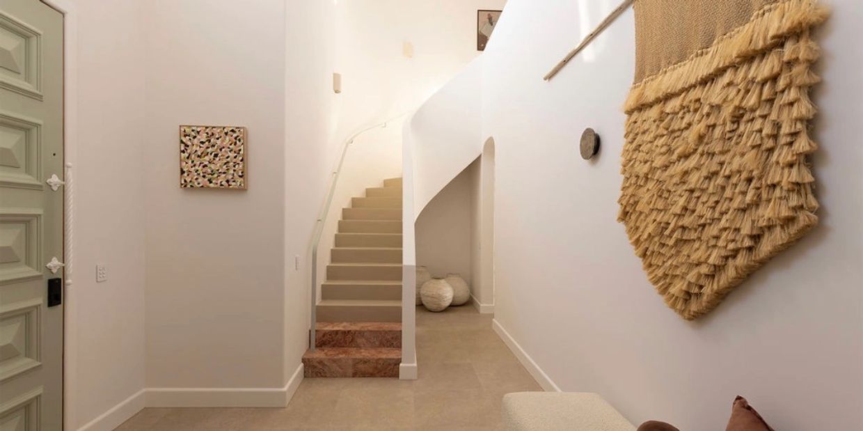 Minimalist hallway with beige stairs and textured wall hanging.