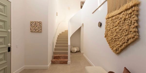 Minimalist hallway with beige stairs and textured wall hanging.