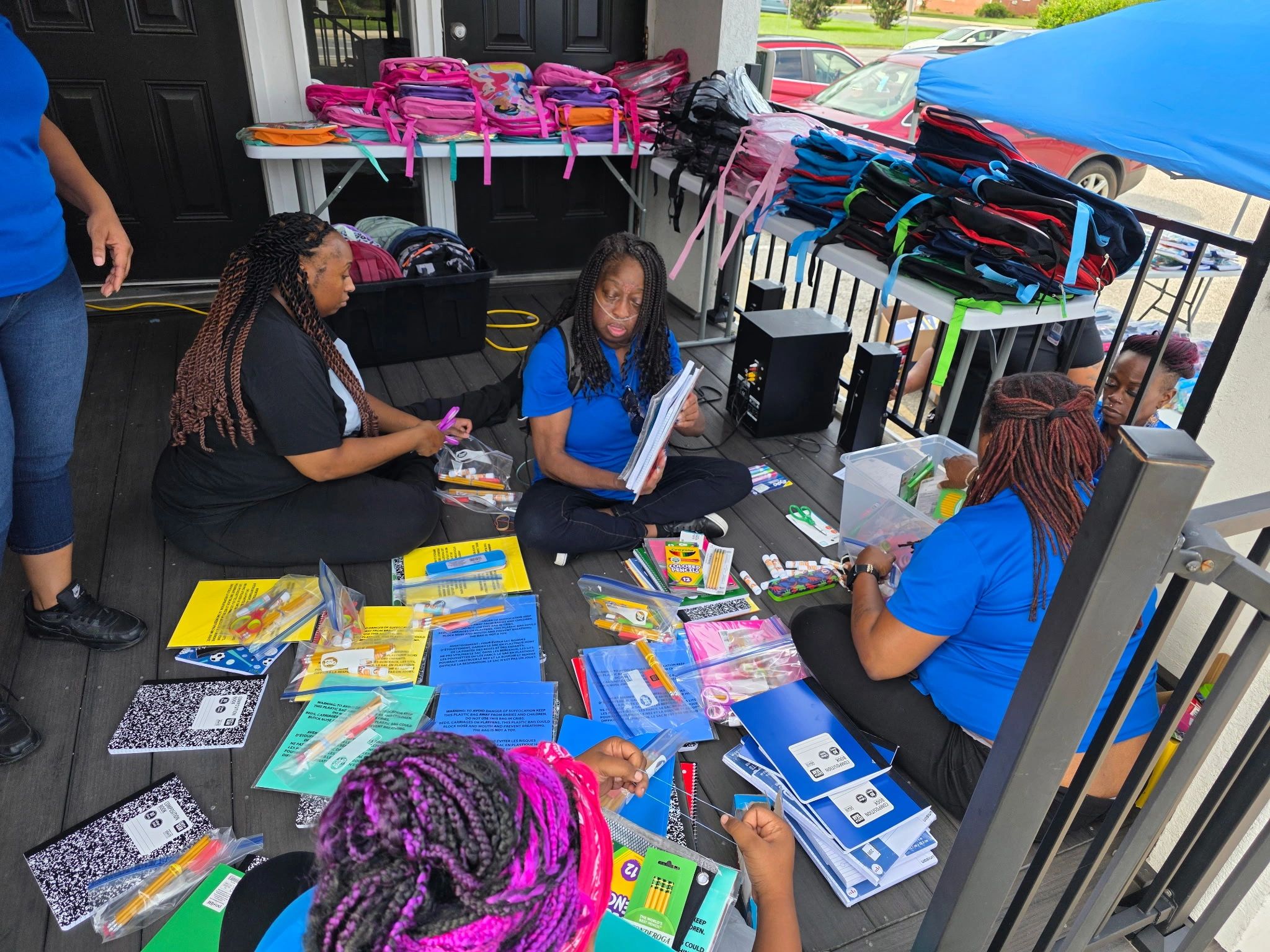 People organizing school supplies on a porch.