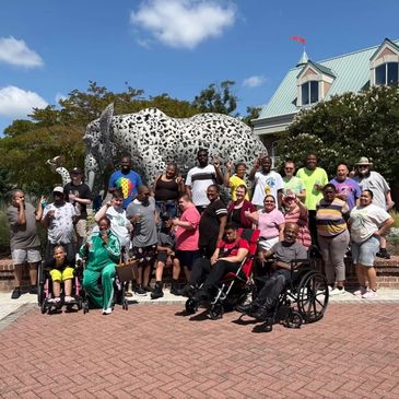 Group photo of diverse people in front of a large cat statue.