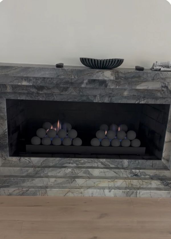 Modern fireplace with a gray marble surround and decorative flames.