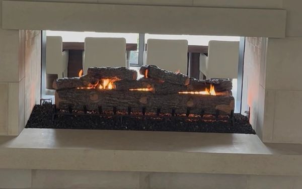 Modern gas fireplace with flames and white chairs visible.
