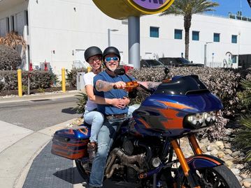 Two people on a custom motorcycle in front of Hard Rock Hotel.