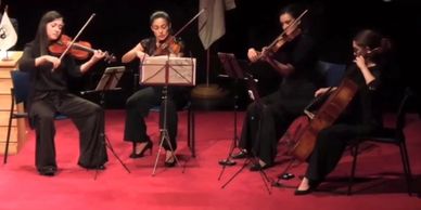 Cuarteto de cuerdas realizando concierto en un teatro 