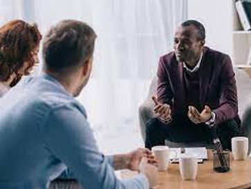 Three people engaged in a serious discussion in a cozy room.