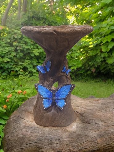 Decorative wooden stool with blue butterfly designs in a garden.