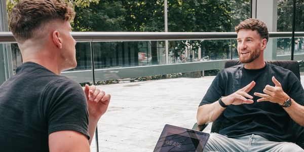 Two men having a discussion outside with a laptop.