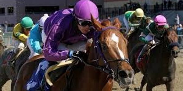 Jockeys racing horses on a dirt track.