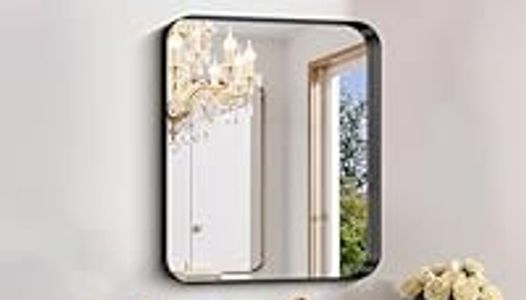 Square mirror with rounded corners reflecting a chandelier and window.