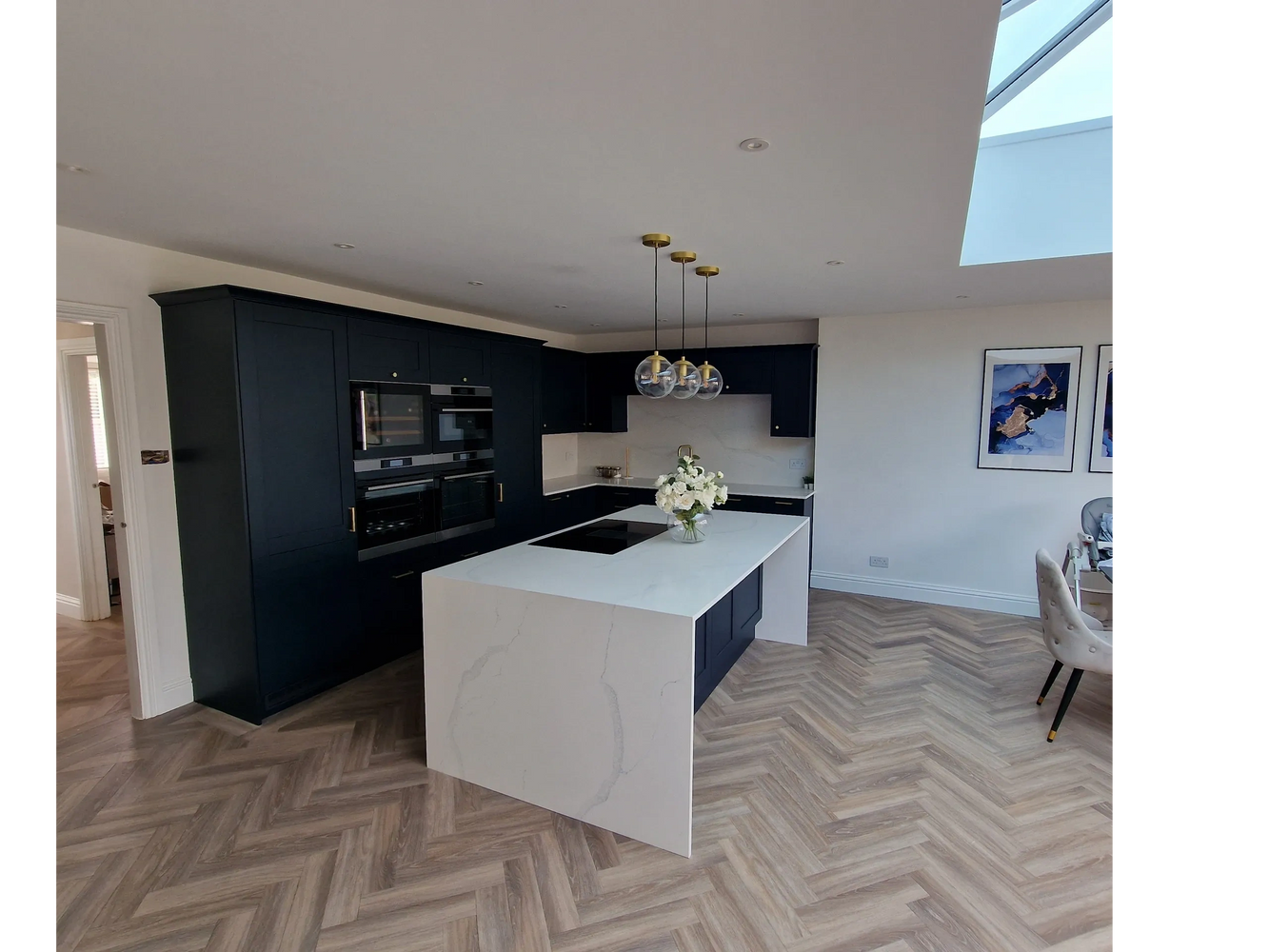 Modern kitchen with black cabinets, white marble island, and stylish pendant lights.