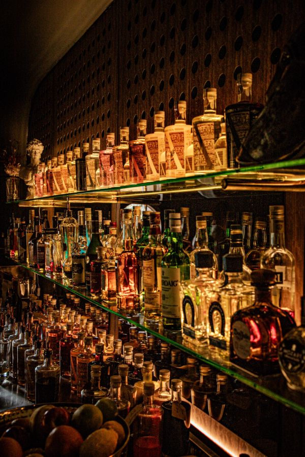Shelves filled with various bottles of alcohol in a dimly lit bar.
