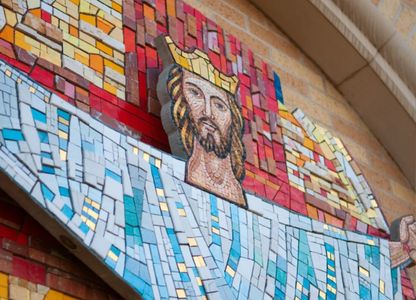 Mosaic artwork of Jesus with outstretched arms on a wall.