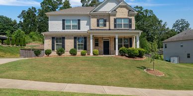 Two-story suburban house with brick and siding exterior and a well-maintained lawn.