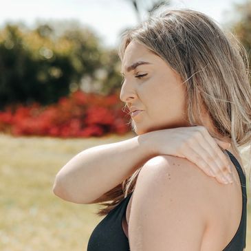 Woman experiencing shoulder discomfort and restricted movement.