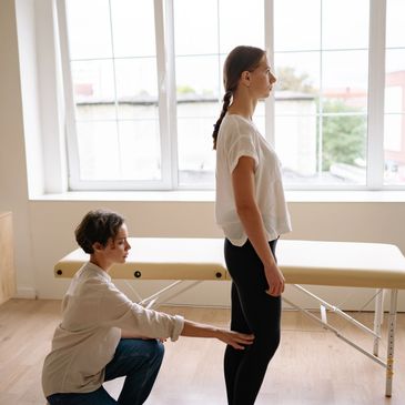 Therapist assessing a client’s posture and range of motion before remedial massage.

