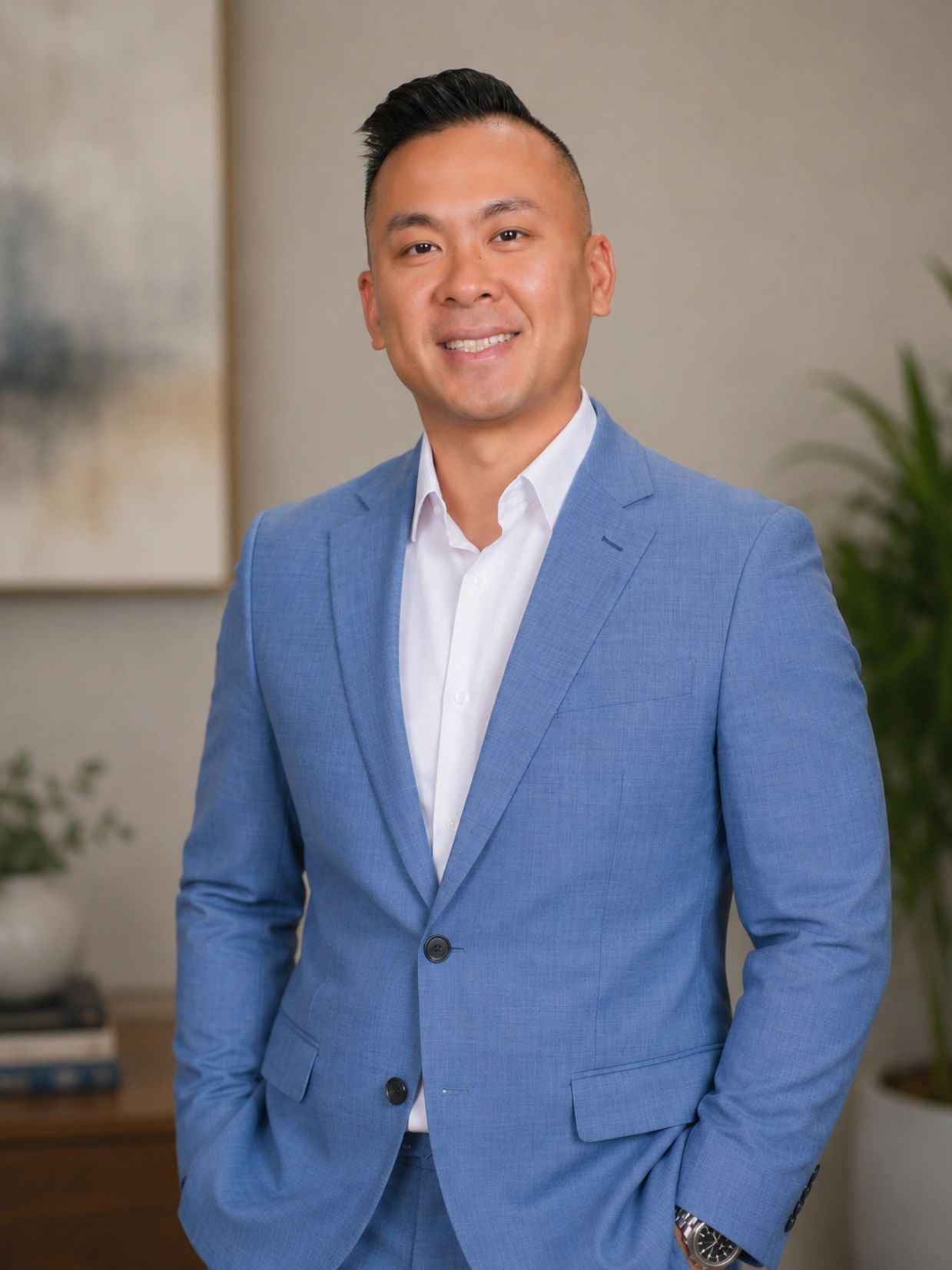 A confident man in a blue suit smiling in an indoor setting.