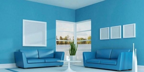 Modern living room with blue sofas and vibrant blue walls.