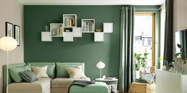 Modern living room with green accent wall and stylish furniture.