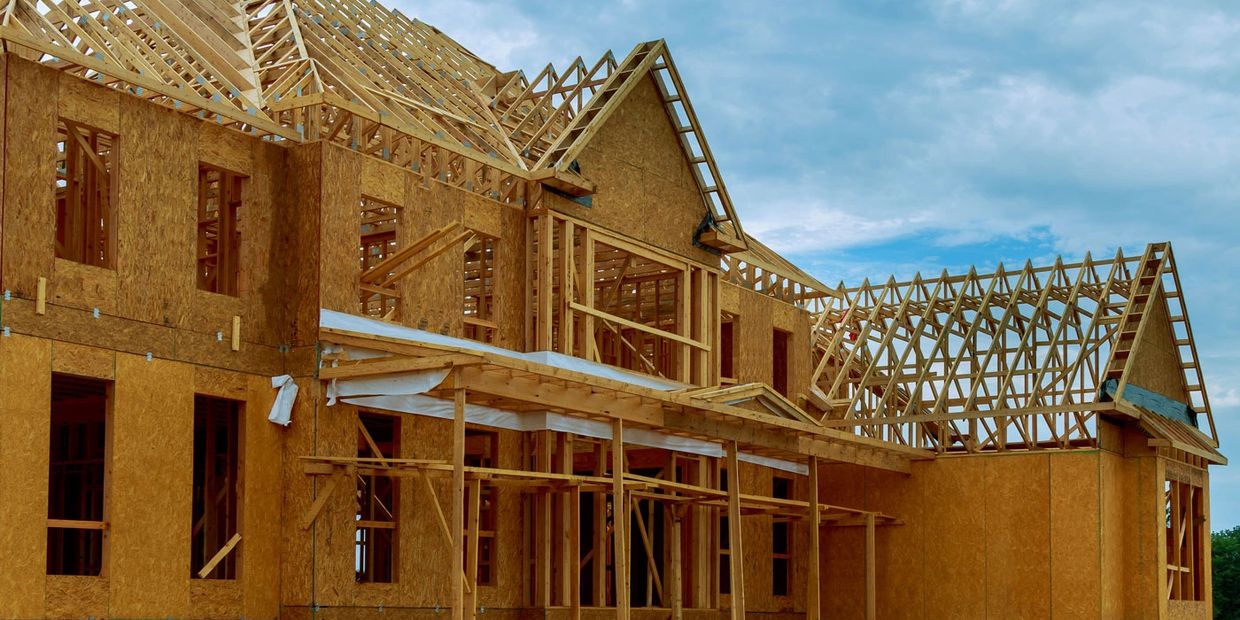 Wooden frame of a house under construction against a cloudy sky.