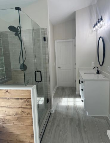 Modern bathroom with glass shower and wooden accents.