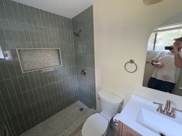 Modern bathroom with tiled shower and white fixtures.