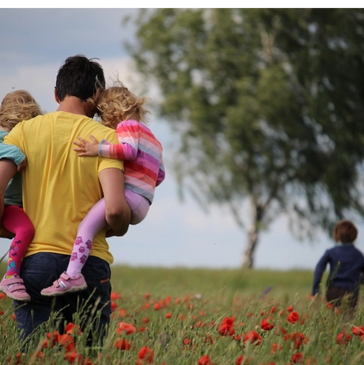 man holding children in field