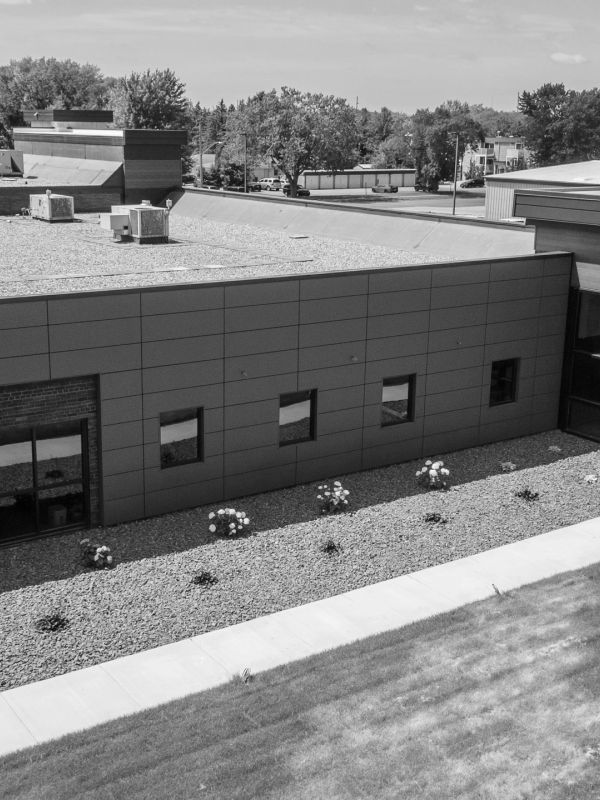 Modern building with small garden beds and gravel area.