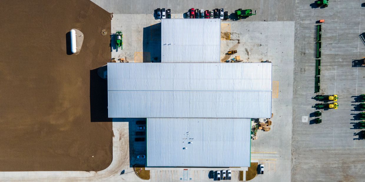 Aerial view of a warehouse with vehicles and farm equipment.