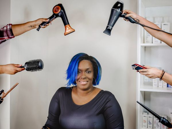 Woman getting her hair styled by multiple stylists.