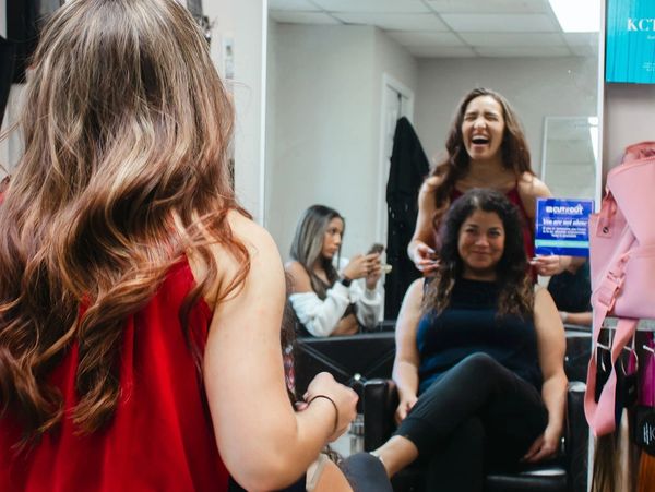 Women smiling and chatting in a dressing room with mirrors.
