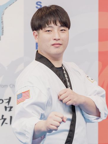 A martial artist in a white uniform posing with a fist forward.