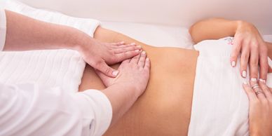 Hands performing abdominal massage on a person.