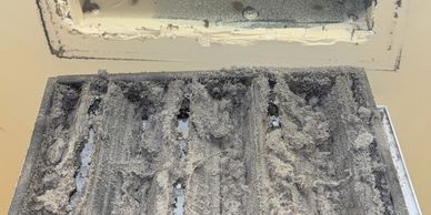 Close-up of lint buildup being removed from a vent to prevent fire hazards and improve air quality.