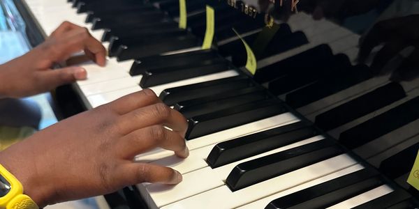 Hands playing piano keys with yellow sticky notes.